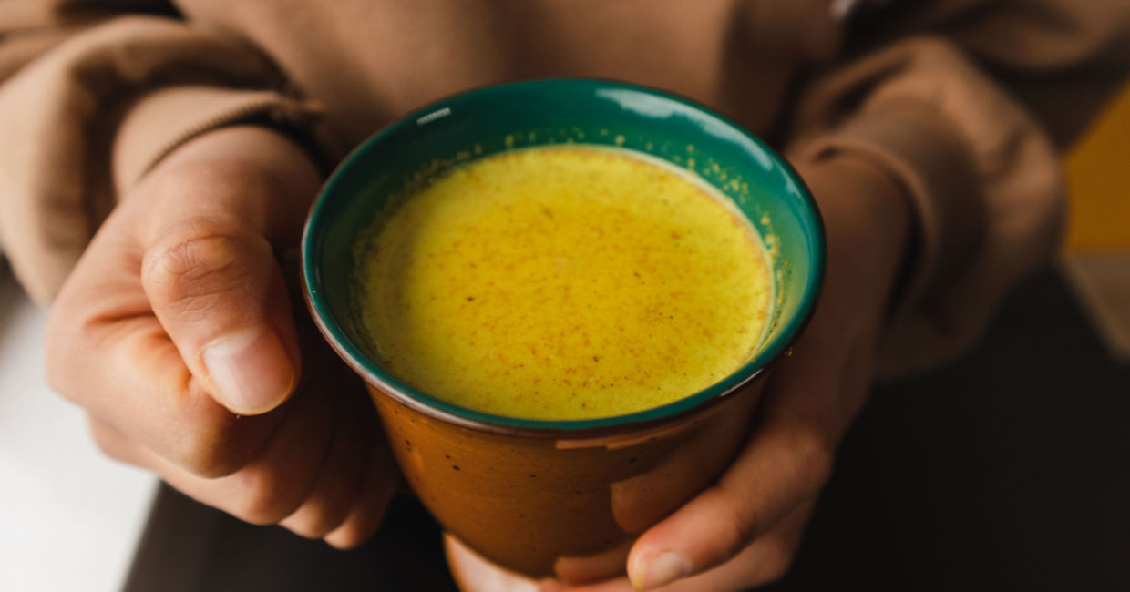Man holding a cup of turmeric tea.