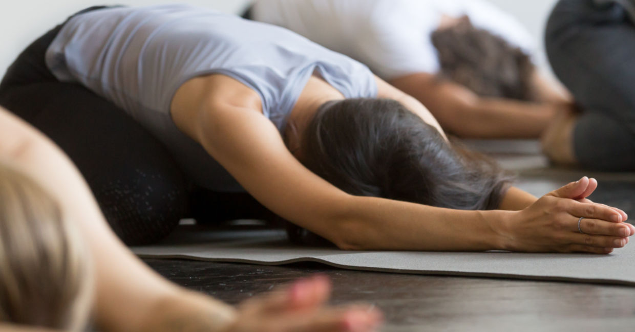 Yoga class practicing a variation of the child's pose.