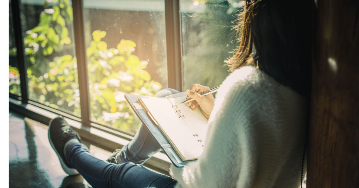 Woman writing her thoughts down in a journal.