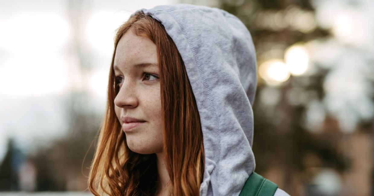 Gen Z young woman wearing a hoodie outdoors.