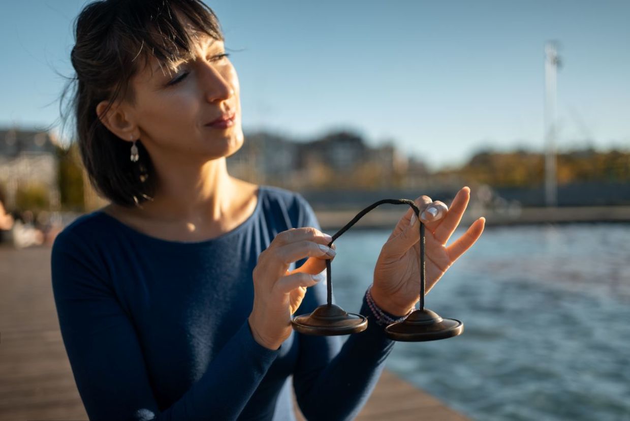Woman holding a tingsha bell instrument for vibration.