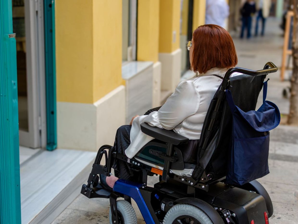 Woman cannot access a store that does not have a wheelchair ramp.
