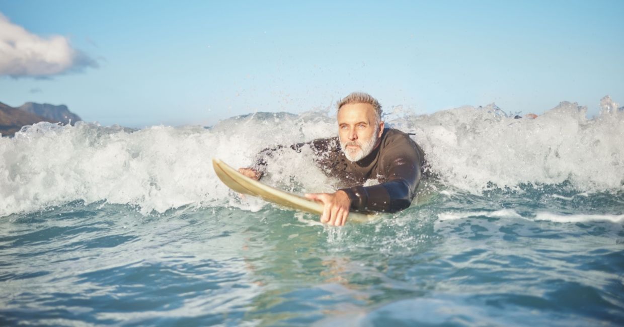 a senior man bodyboarding in the surf.