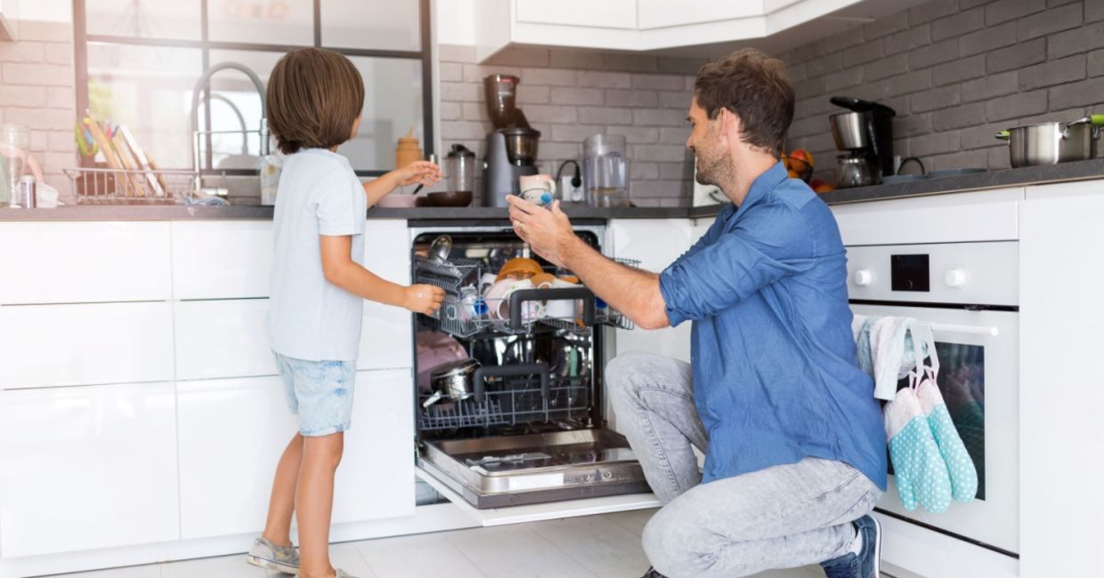 Father and son load a dishwasher.