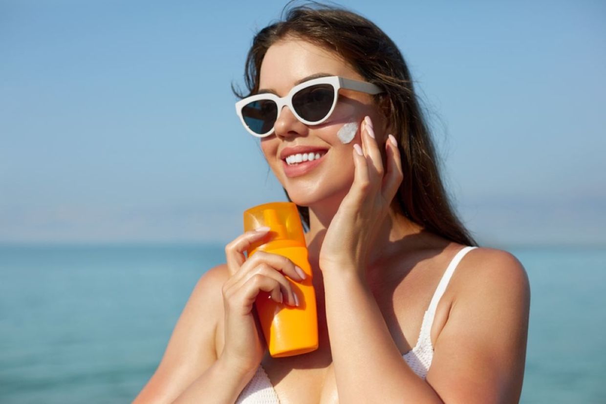 A woman puts on sunscreen on a sunny day.