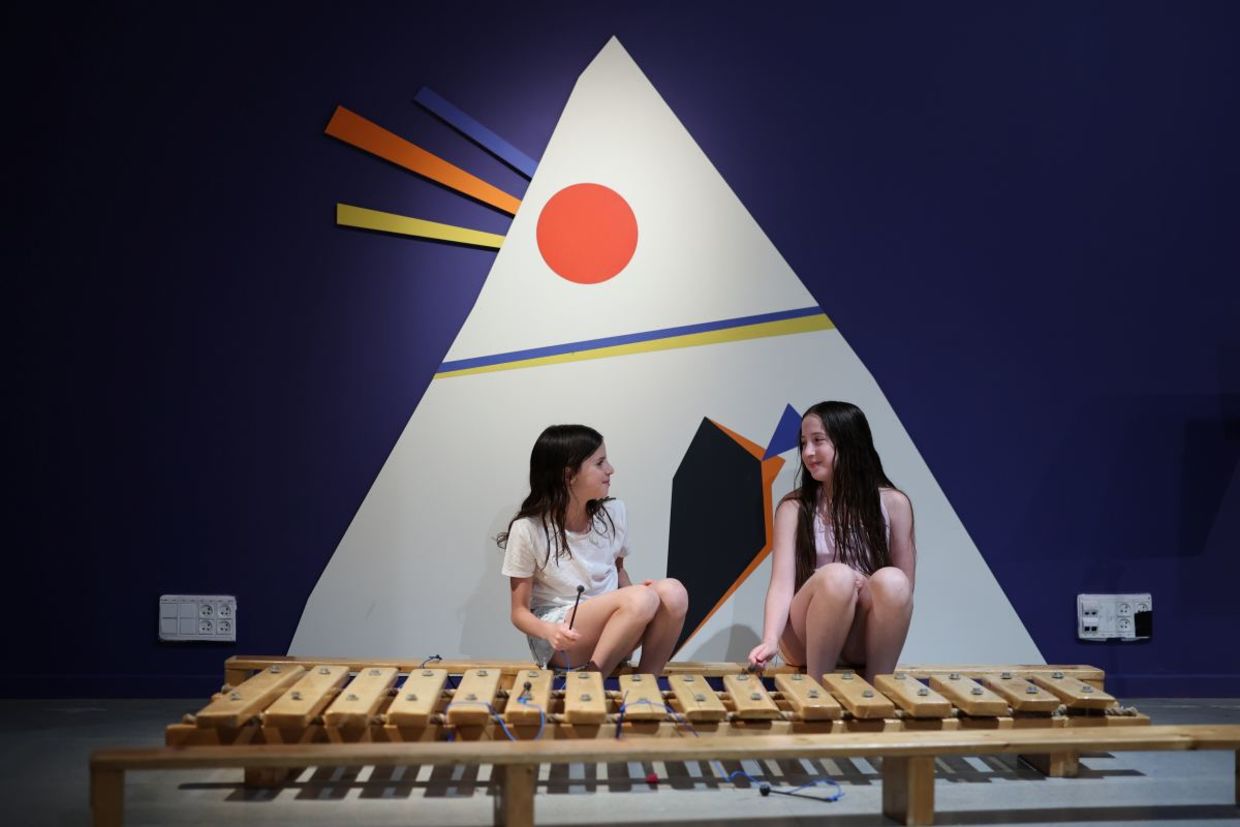 Two girls play with an instrument.