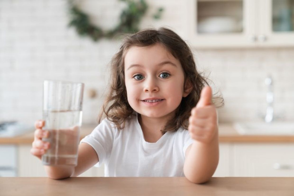 A cute girl enjoying a glass of fresh water.