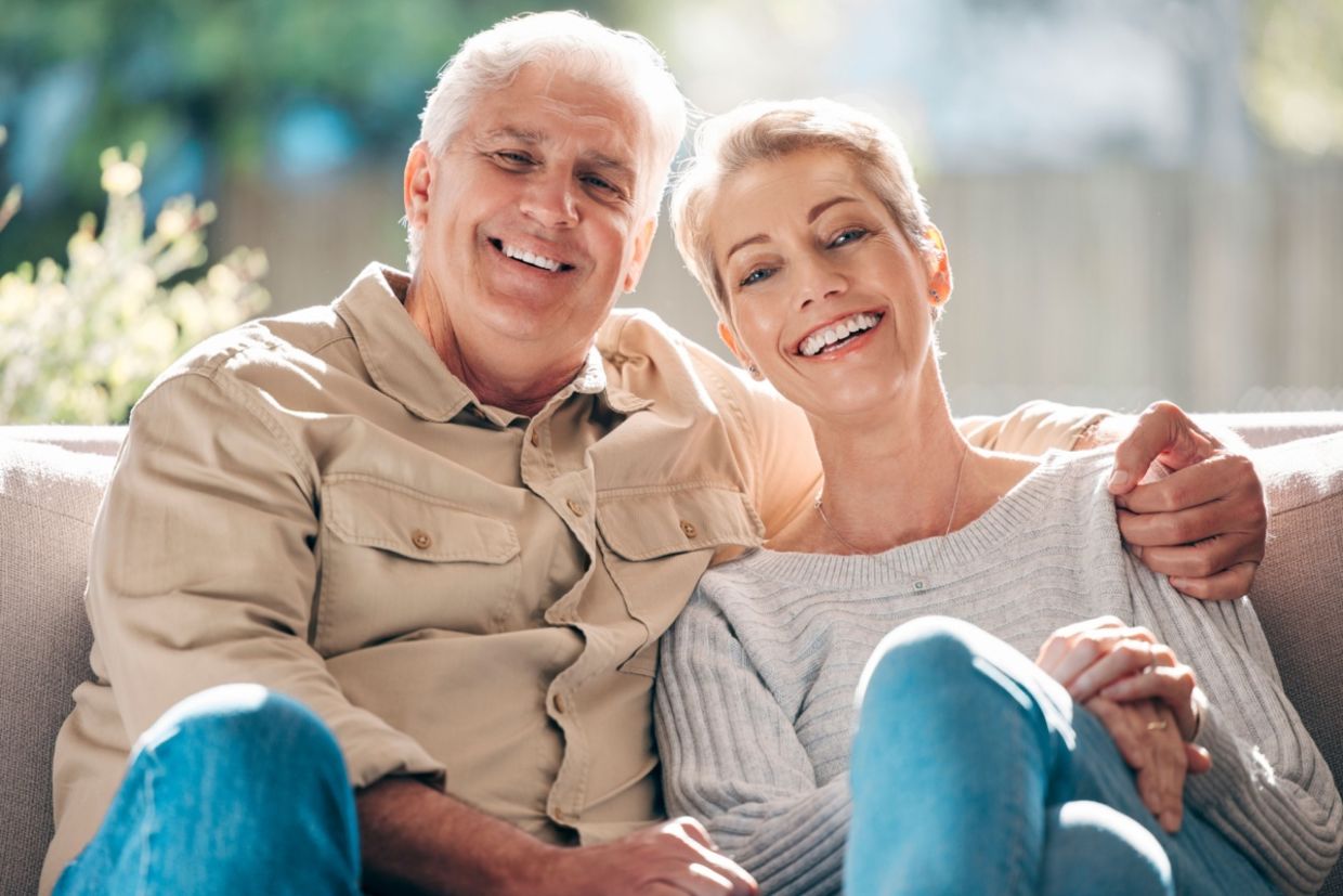 A senior couple sits on a couch.