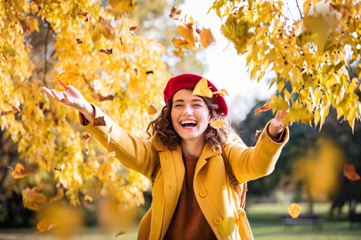 A woman throws leaves in the air.