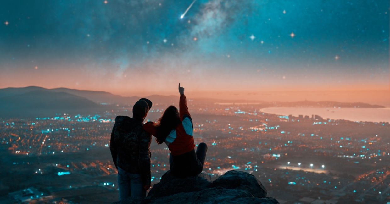 Couple watching shooting stars from a rooftop.