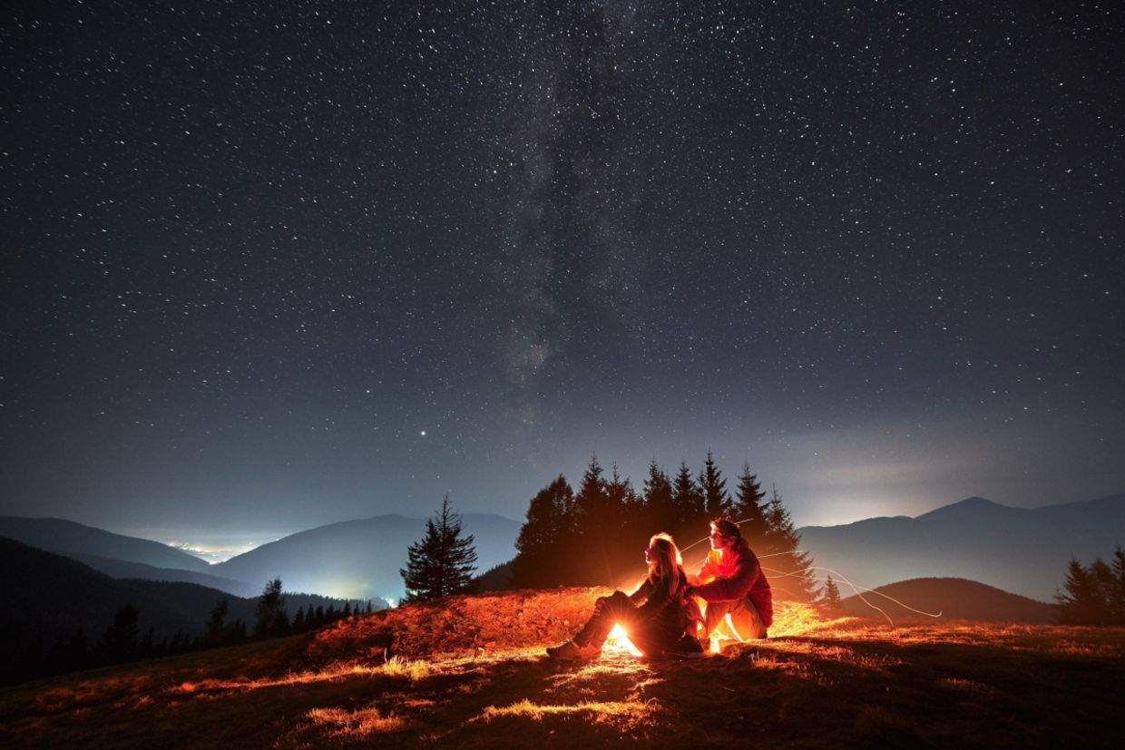 Two people sit under the stars.