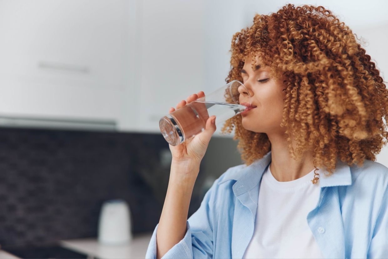 A woman drinks water from a glass.