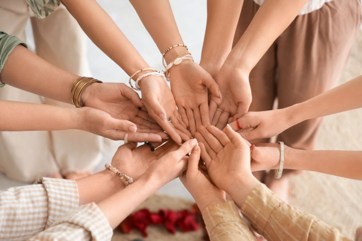 Young girls stand in a circle with their hands together.