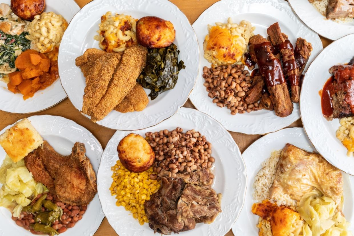 A soul food feast with a variety of dishes served on numerous plates.