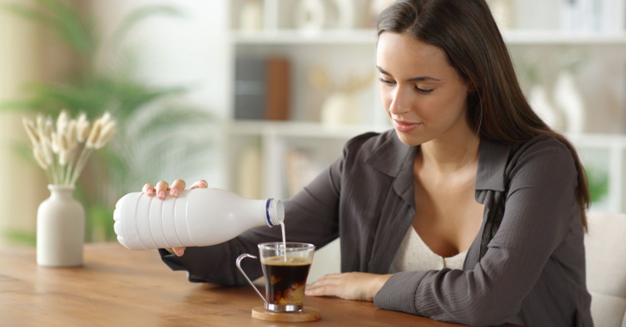 Woman adding milk to her coffee.