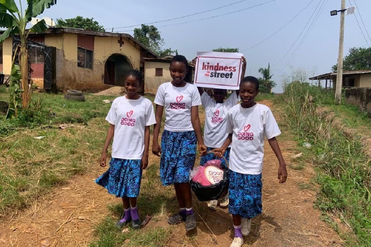 Children wearing Good Deeds Day shirts walk through a neighborhood carrying a “Kindness in the Street” sign in Nigeria.