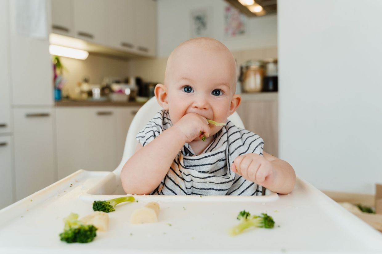 A baby boy eats vegetables.