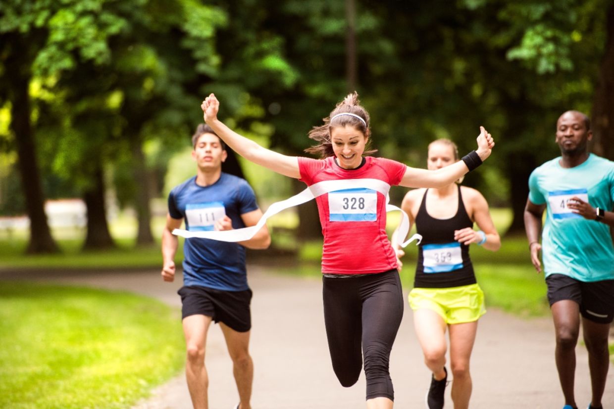 A woman runs in the crowd and crosses the finish line.