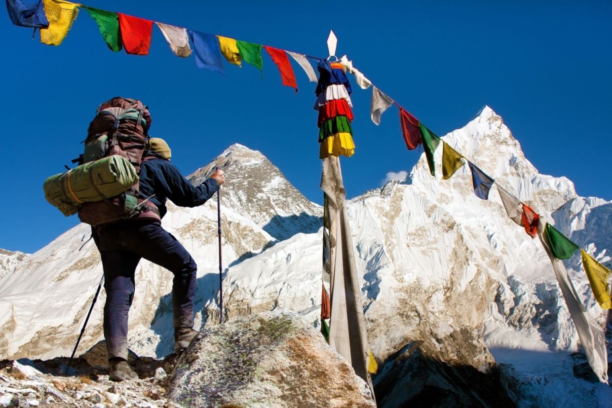 A view of Everest with hiker and buddhist prayer flags.