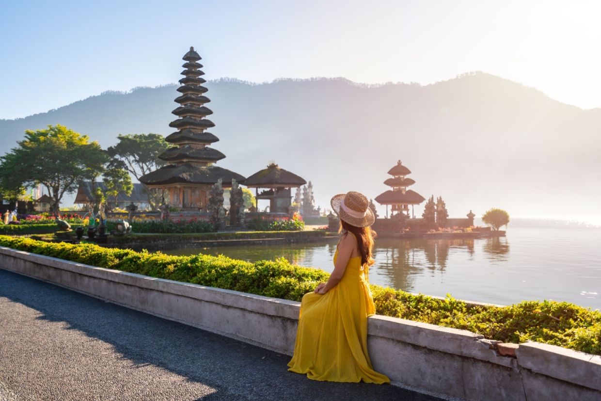 A female tourist relaxing and enjoying a beautiful view of a temple in Bali.