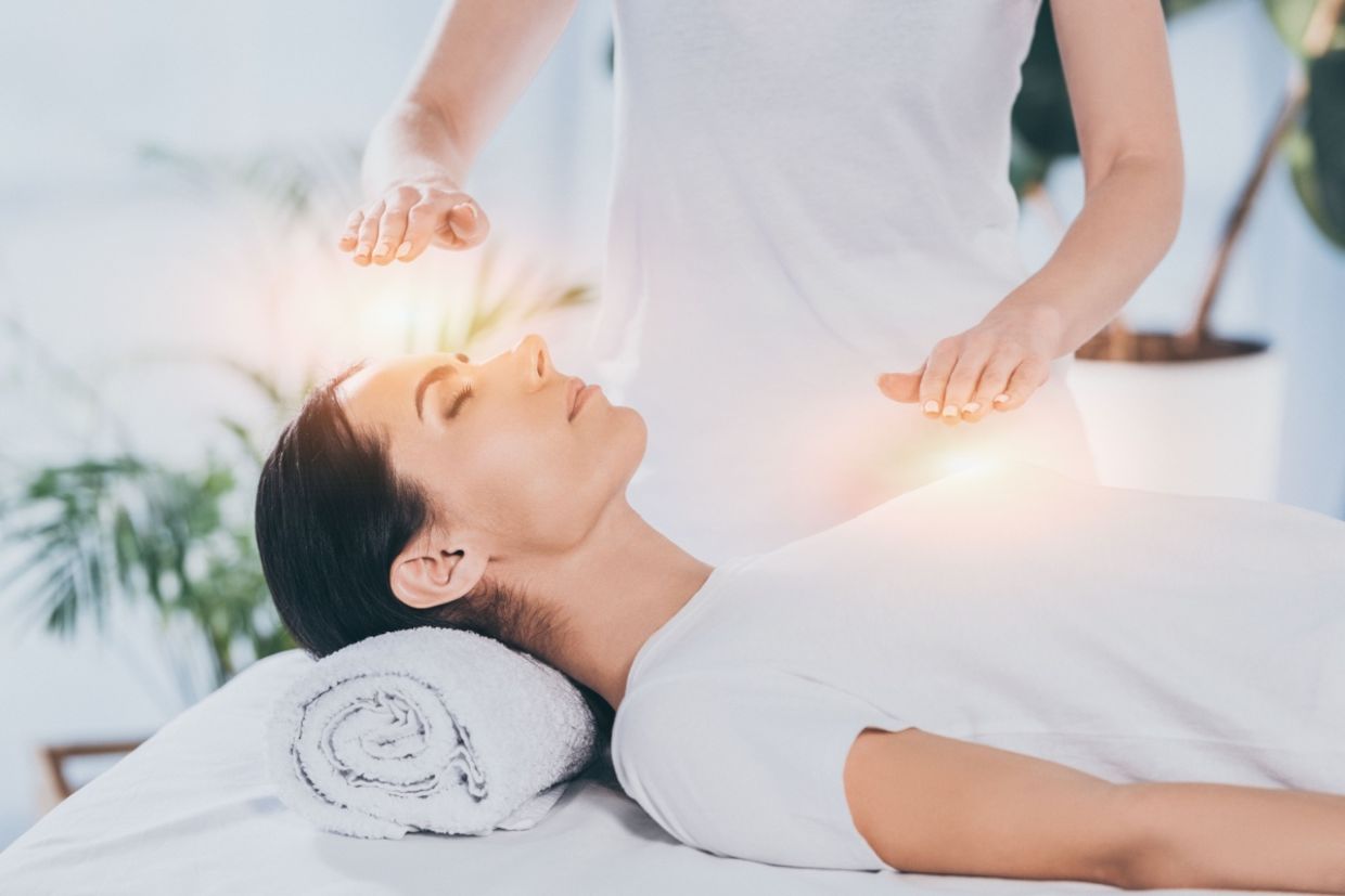 A calm woman receives reiki healing therapy.