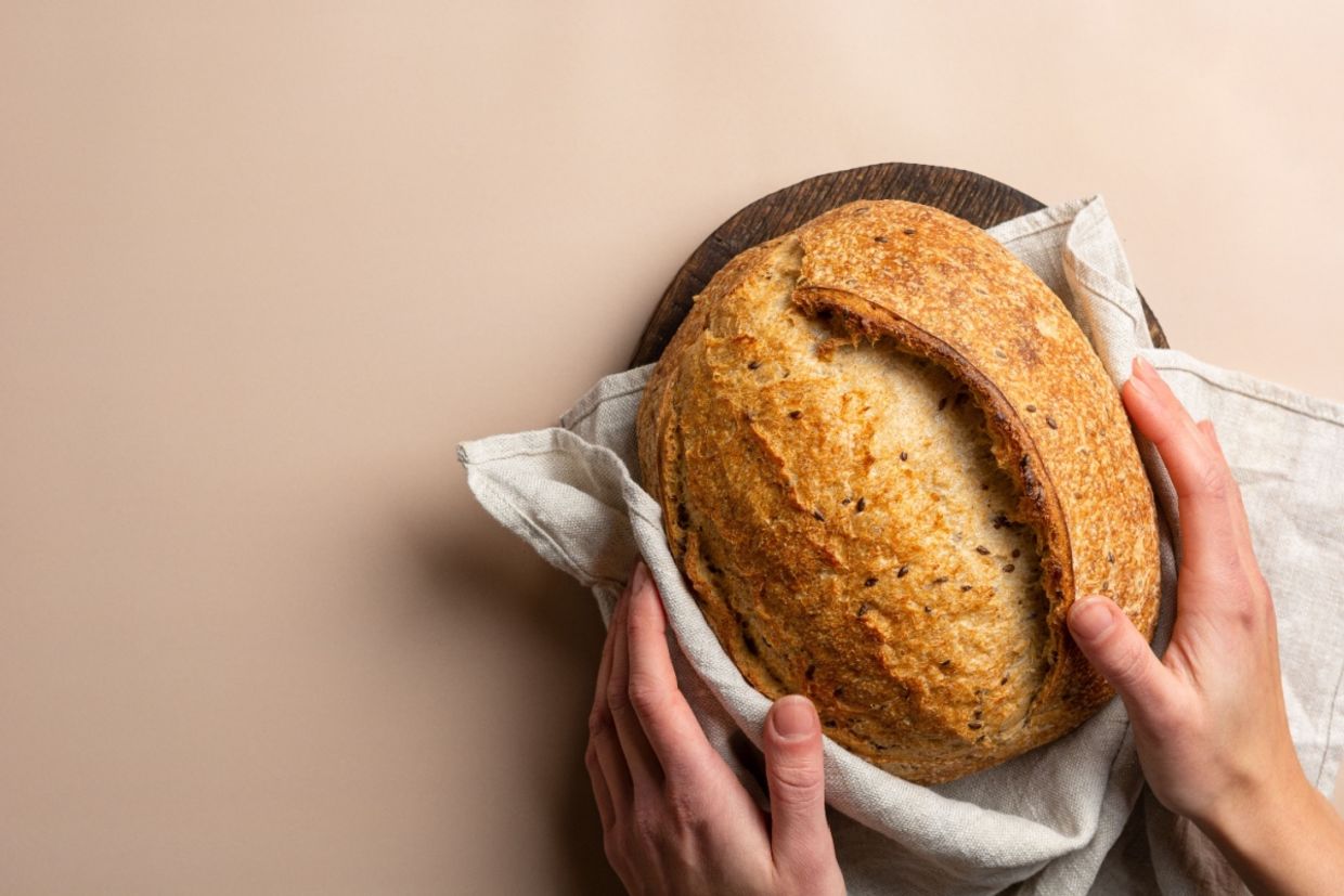 A person holds a loaf of sourdough bread.