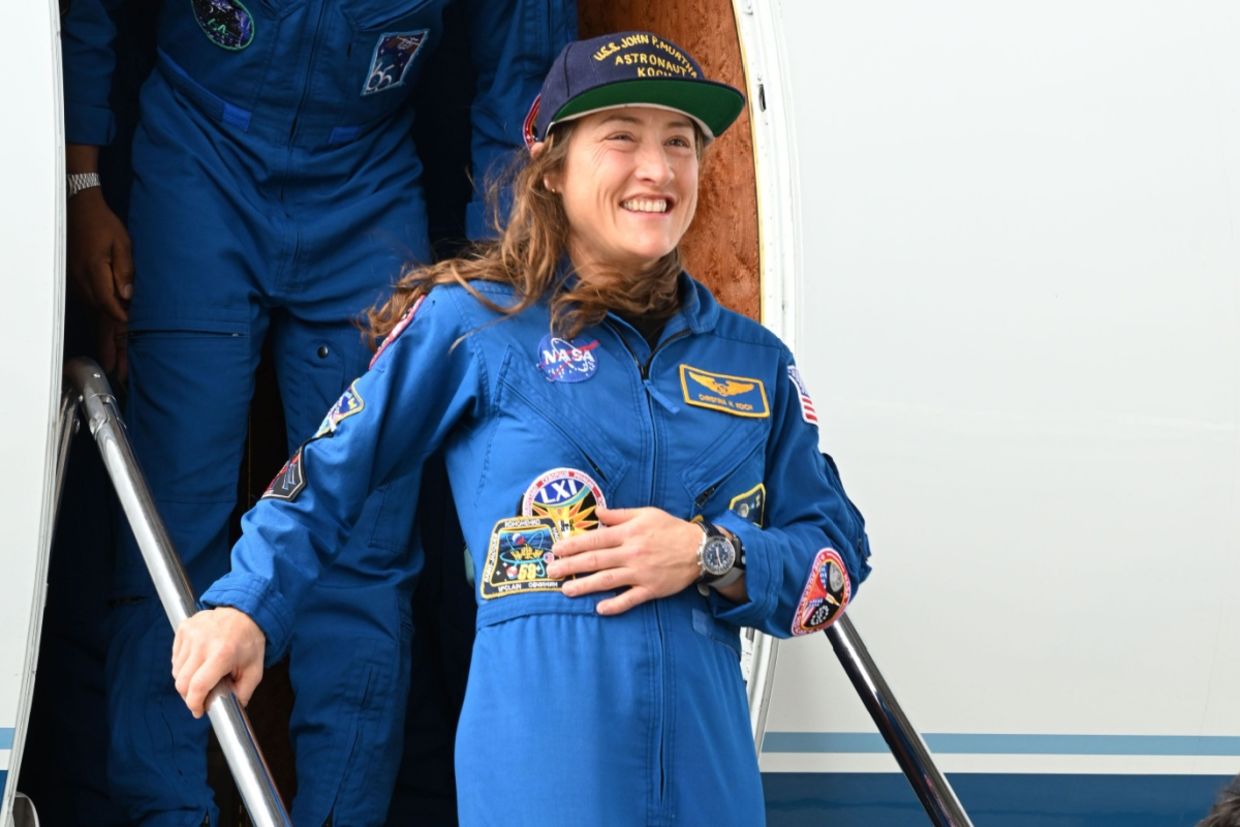 Christina Koch stands and smiles during the Artemis-02 crew return ceremony.