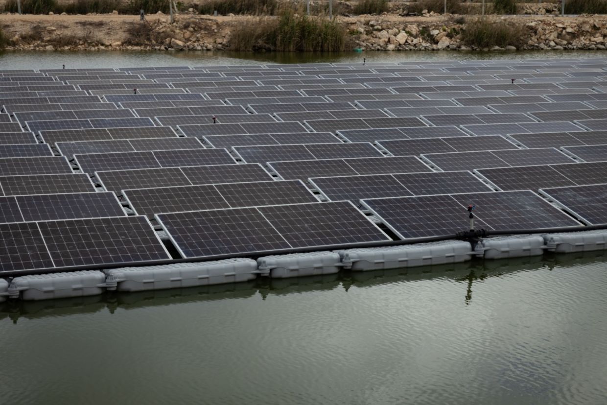 A solar panel system installed above a fish pond.