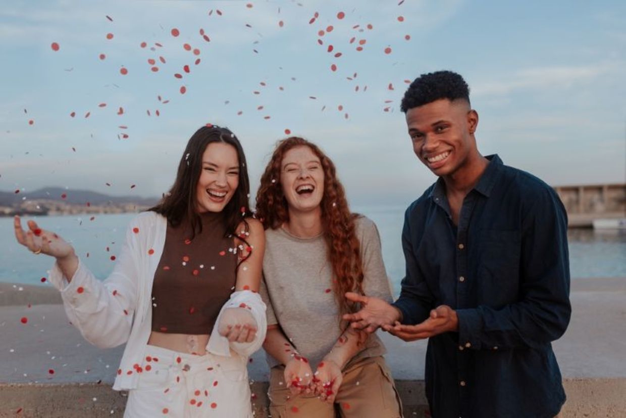 Cheerful young friends photographed by the sea, enjoying life.